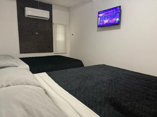 a bedroom with two beds and a tv on the wall at Punta Lobos in Reynosa