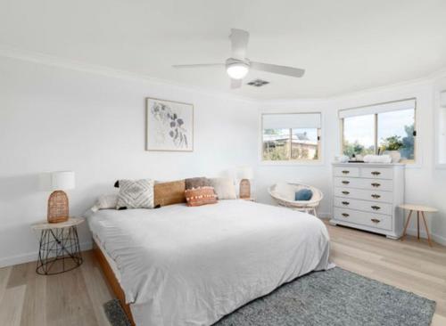 a white bedroom with a bed and two windows at Beach Street Stay in Harrington