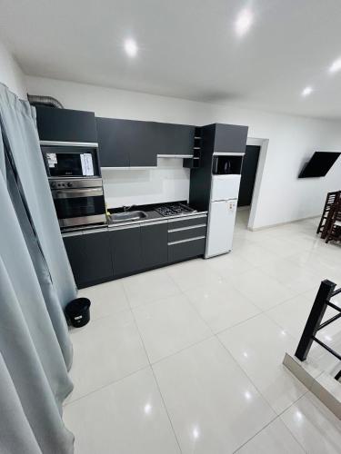 a kitchen with black and white appliances and a white tile floor at Departamento ESTRADA ideal para pasajeros en tránsito, viajes laborales o estadías cortas Ubicado en Ezeiza, a solo 20 minutos del Aeropuerto Internacional Ministro Pistarini, ofrece comodidad y practicidad para hasta 4 personas in Tristán Suárez