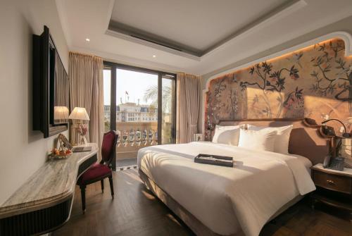 a hotel room with a bed and a desk and a window at Heritage Ham Long Hotel and Spa in Hanoi
