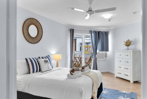 a white bedroom with a bed and a mirror at Northshore Palms Apartment in Cairns North