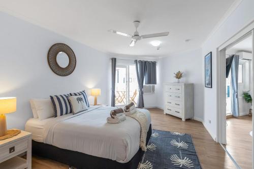 a white bedroom with a bed and a dresser at Northshore Palms Apartment in Cairns North