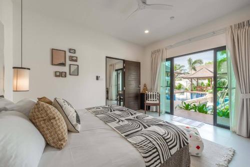 a bedroom with a large bed and a balcony at Tranquil 4BR Garden Pool Oasis - Layan Beach in Laguna Phuket