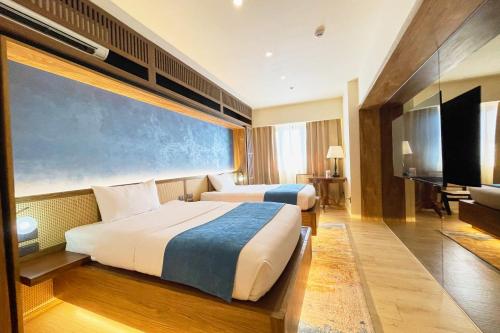 a hotel room with two beds and a flat screen tv at Elijah Hotel Dasmarinas City Cavite in Dasmariñas