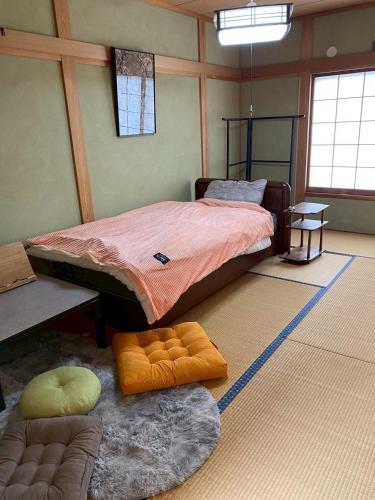 a bedroom with a bed and two ottomans in it at つむぐ家2 in Ueda