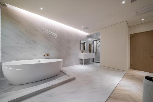 a white bathroom with a tub and a sink at 루엠호텔안산 in Ansan