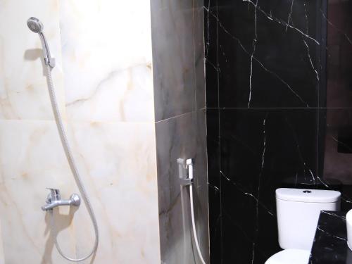 a bathroom with a shower with a toilet and black tiles at Grand Elhajj Banten in Tjipondoh Tiga