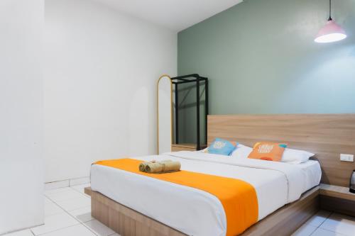 a bedroom with a large bed with an orange blanket at Sans Stay Eskole Lampung in Geruntang