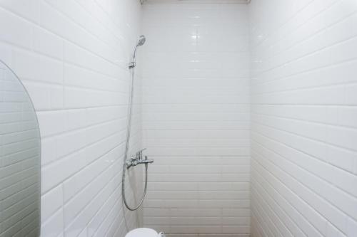 a white bathroom with a shower with a toilet at Sans Stay Eskole Lampung in Geruntang