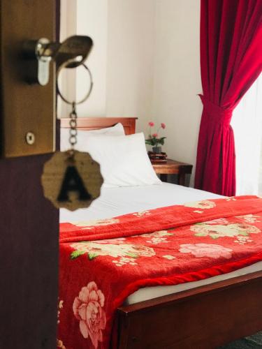 a bedroom with a bed with a red blanket and a lamp at Stay Logi Nanuoya in Nanu Oya