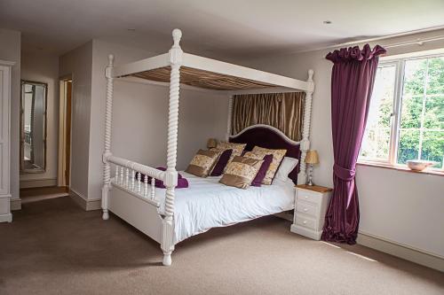 een slaapkamer met een wit hemelbed met kussens bij Stoodleigh Court Coach House in Tiverton