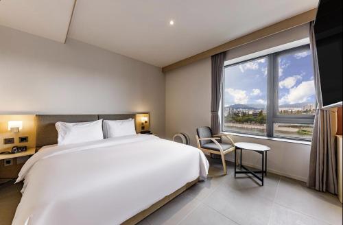 a bedroom with a large white bed and a large window at Daegu Hound Hotel Dongchon Amusement Park in Daegu