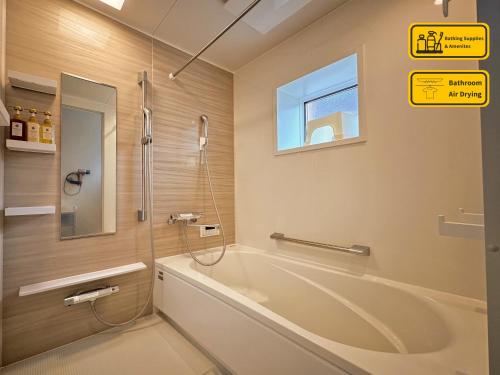 a bathroom with a tub and a shower and a window at Sankando Villa Hotel in Fujikawaguchiko