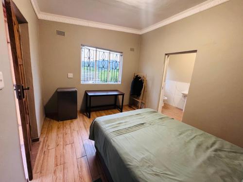 a bedroom with a bed and a window and a table at Pholanathi Lodge in Cliffdale