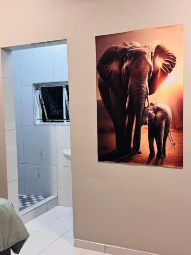 a painting of an elephant and a baby elephant in a bathroom at Pholanathi Lodge in Cliffdale