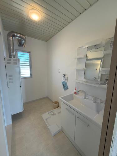 a white bathroom with a sink and a mirror at OtowaBase in Kofu