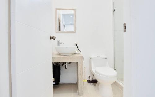 a white bathroom with a toilet and a sink at Butterfly House - Centric 2BR with shared pool in Puerto Viejo