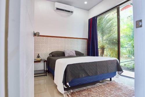 a bedroom with a bed in a room with a window at Sloth House - Centric 2BR with shared pool in Puerto Viejo