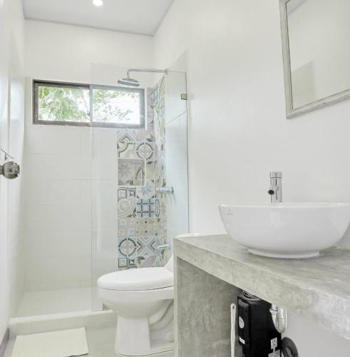 a white bathroom with a sink and a toilet at Sloth House - Centric 2BR with shared pool in Puerto Viejo