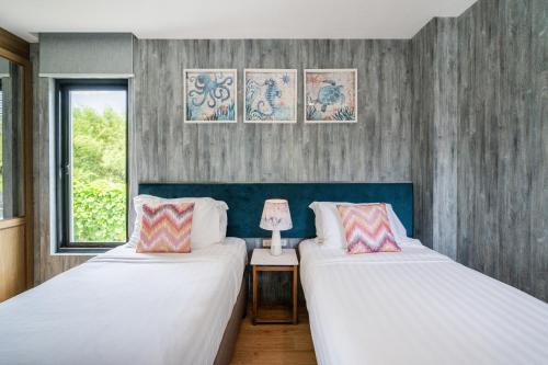 two beds in a room with two lamps and a window at Movenpick Residences 4-Bedroom Pool Villa Beach Access, Na Jomtien Pattaya in Na Jomtien