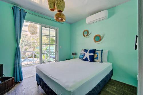 a blue bedroom with a large bed and a window at Casa Caribe Azul - Playa Negra 2BR with AC and pool in Puerto Viejo