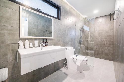 a bathroom with a sink and a toilet and a shower at Movenpick Residences 4-Bedroom Pool Villa Beach Access, Na Jomtien Pattaya in Na Jomtien