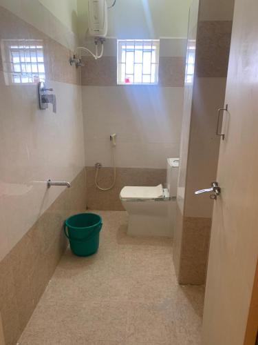 a bathroom with a toilet and a green bucket at KH Residency And Lodging in Punganūru