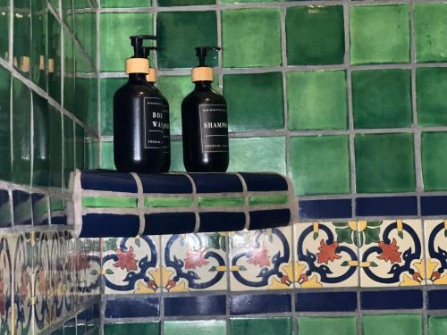 Dos botellas negras en un estante sobre una pared de azulejos en Posada del Cortes, en Loreto
