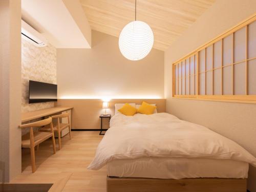 a bedroom with a white bed and a desk and a desk at Yufuin Covaco in Yufu