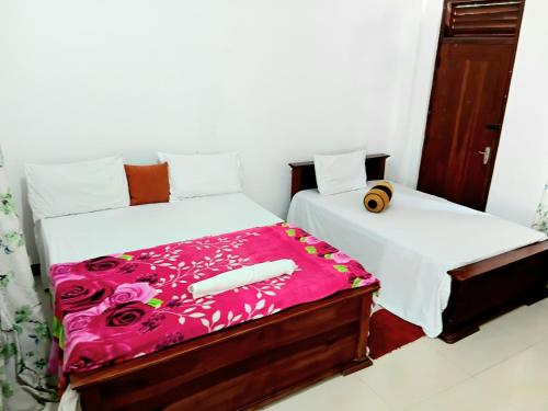 a bedroom with two beds with pink sheets at Ninety Nine Grand Hotel in Badulla