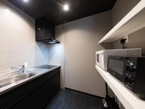 a small kitchen with a sink and a microwave at Yufuin Covaco in Yufu