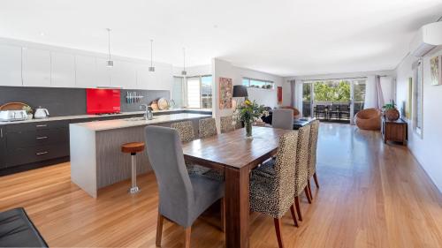a kitchen and dining room with a wooden table and chairs at The Art House in Culburra Beach