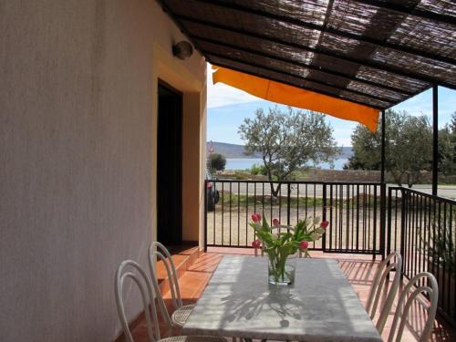 a table with a vase of flowers on a balcony at Apartments and Rooms Degenija in Starigrad-Paklenica