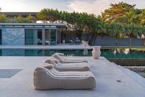 a row of chaise lounges next to a swimming pool at Villa Essenza in Ban Han Pa To