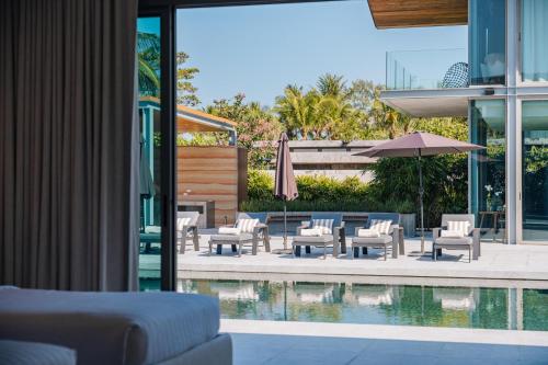a patio with chairs and an umbrella and a pool at Villa Essenza in Ban Han Pa To