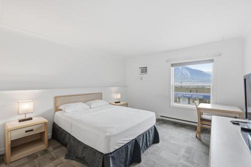 a bedroom with a white bed and a window at Lillooet Hotel Victoria in Lillooet
