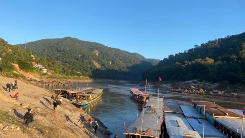 a group of boats are docked on a river at Mekong Backpackers in Pakbeng