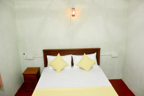 a bedroom with a bed with two yellow pillows at Chenudi Villa Ahangama in Ahangama