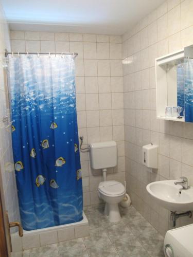 a bathroom with a toilet and a shower curtain with fish at Apartments and Rooms Degenija in Starigrad-Paklenica