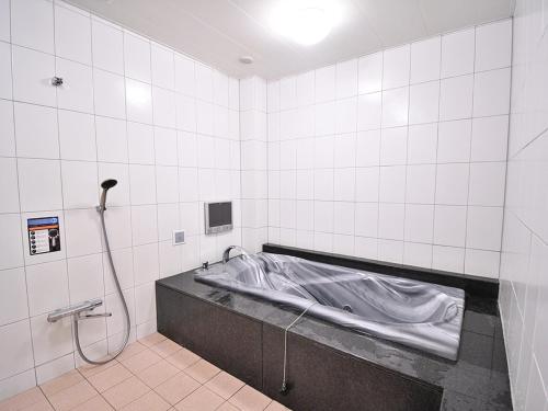 a bathroom with a tub with a shower in it at ホテル ヴォーグ in Kuwana