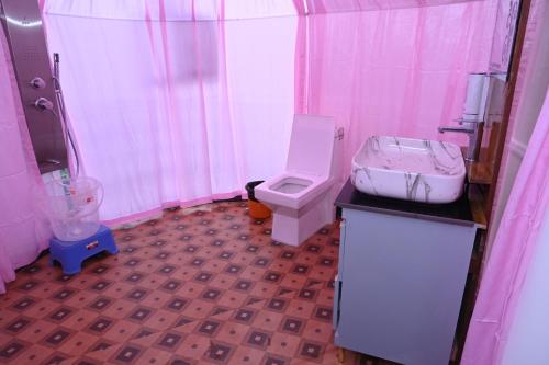 a pink bathroom with a toilet and a sink at Prakriti Hill Resort in Nandaprayāg