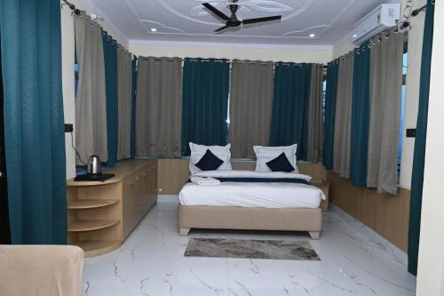 a bedroom with a bed and a desk with a ceiling fan at Prakriti Hill Resort in Nandaprayāg