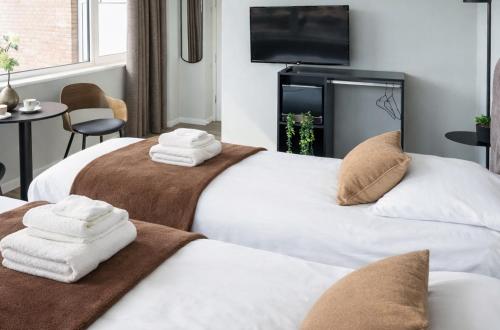 two beds in a hotel room with towels on them at Modern Suite with AC near Breda & Efteling in Raamsdonksveer
