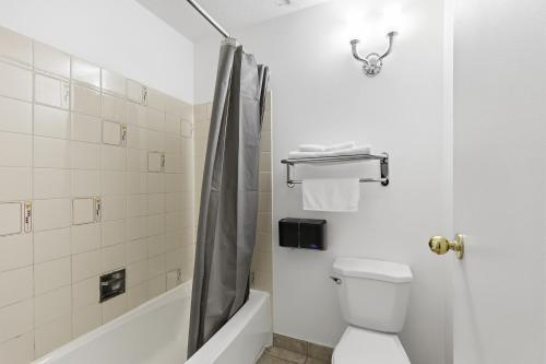 a white bathroom with a shower and a toilet at Lillooet Hotel Victoria in Lillooet