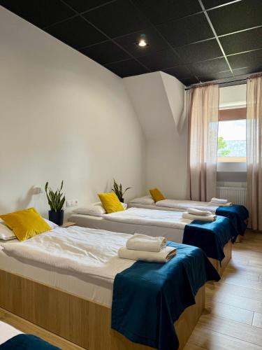 a room with three beds with blue sheets and a window at Podhalanin noclegi in Wadowice