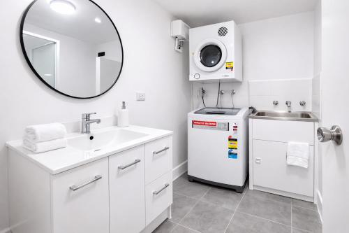 a white bathroom with a sink and a refrigerator at Beachside Garden Apt Beach Scarborough with Parking in Perth