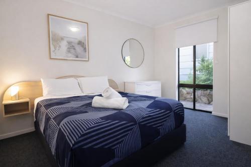 a bedroom with a blue and white bed with a mirror at Beachside Garden Apt Beach Scarborough with Parking in Perth