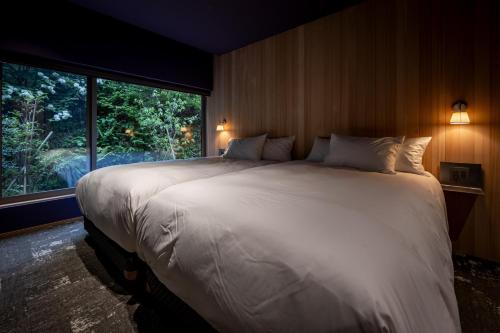 a large white bed in a room with a window at 左京山SAkyozan in Takayama