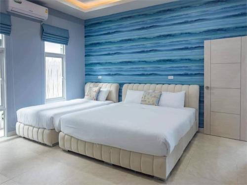 two beds in a bedroom with a blue wall at Chern Mar Pool Villa Cha-am in Cha Am