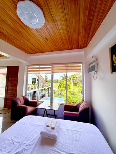 a bedroom with a bed and two chairs and a table at TUBURAN Poolside in Nagsulang